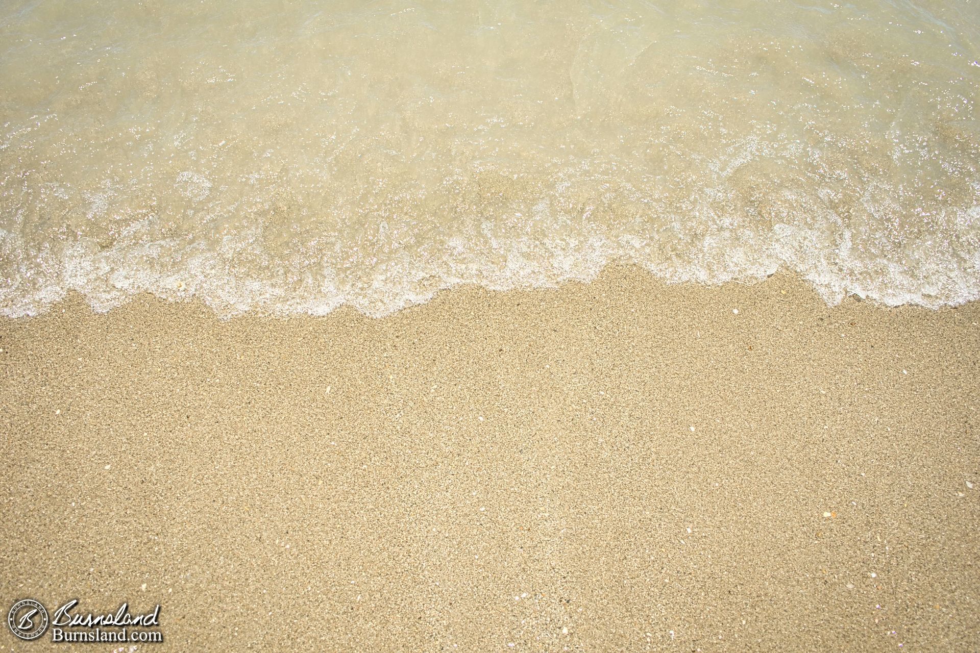 The edge of a wave rolls onto the sand