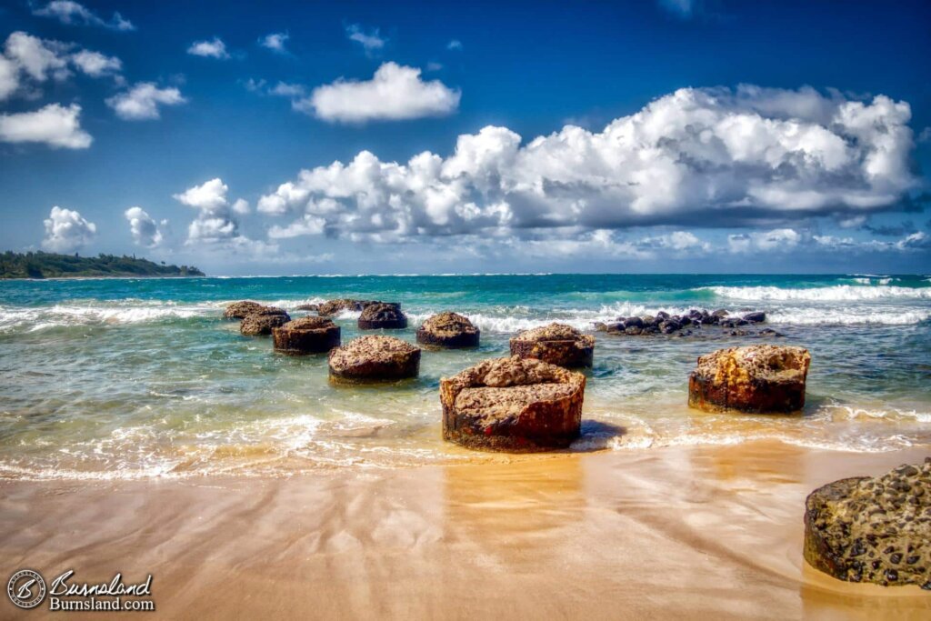 The remains of an old pier lead out into the water at Anahola Beach Park on the island of Kauaʻi in Hawaiʻi