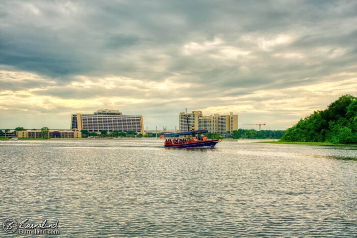 A boat cruises along on Bay Lake at Walt Disney World, with the Contemporary Resort in the background