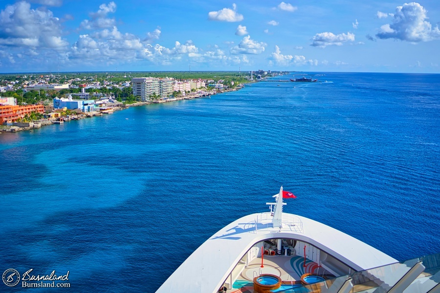 A view of the bow of the Disney Fantasy, some very blue water, and the coast of Cozumel, Mexico, as seen during our 2022 Disney Cruise.