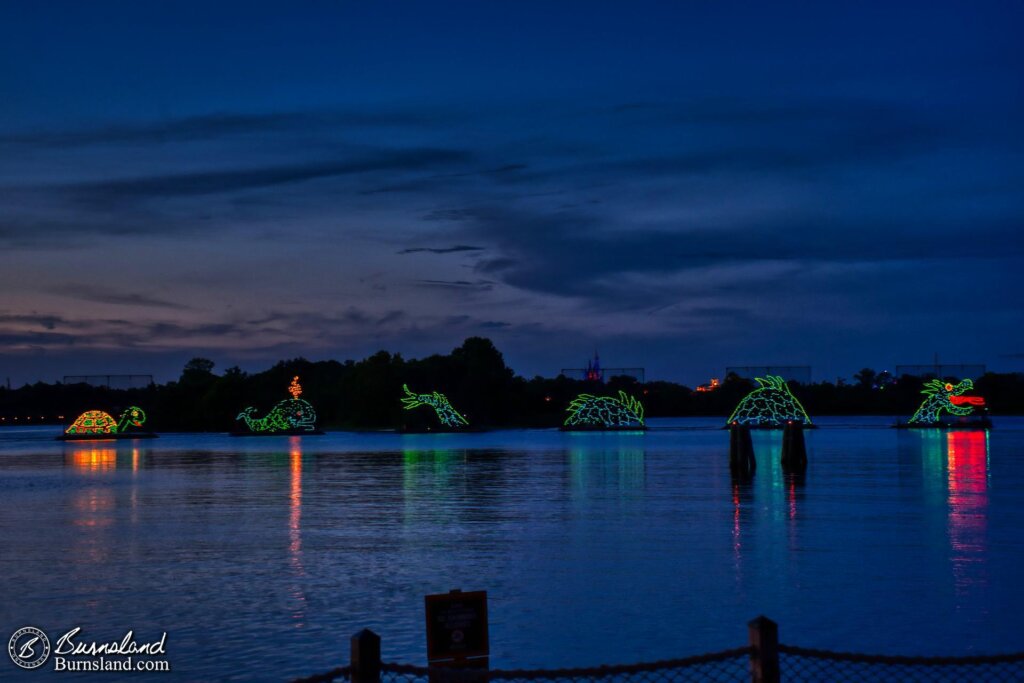 The Sea Monster, Whale, and Turtle floats of the Electrical Water Pageant cruise past the beach at the Polynesian Village Resort at Walt Disney World