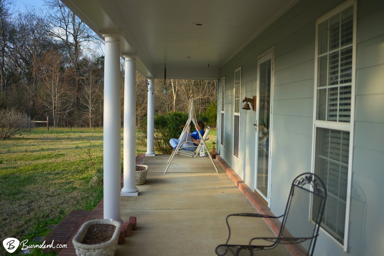 A distant view of Laura in the front porch swing