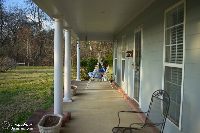 A distant view of Laura in the front porch swing