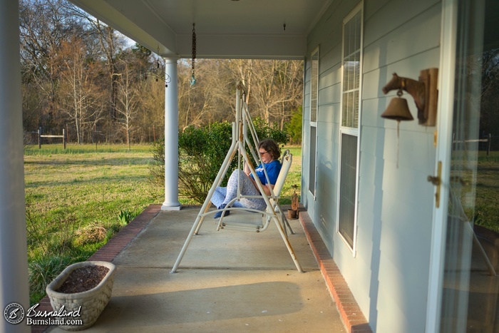 Laura sits in the front porch swing on a beautiful spring afternoon