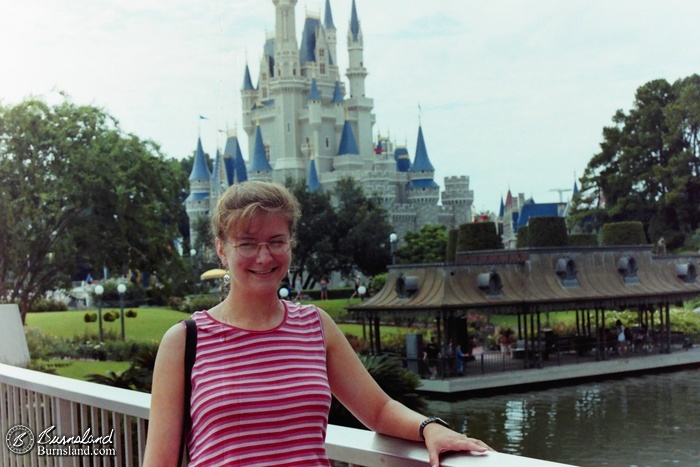 Laura stands on the Tomorrowland bridge with Cinderella Castle in the background at the Magic Kingdom at Walt Disney World from 1996.