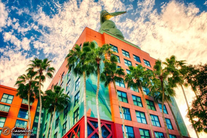 A blue sky, clouds, and a giant dolphin are above palm trees and terracotta colors at the Walt Disney World Dolphin hotel