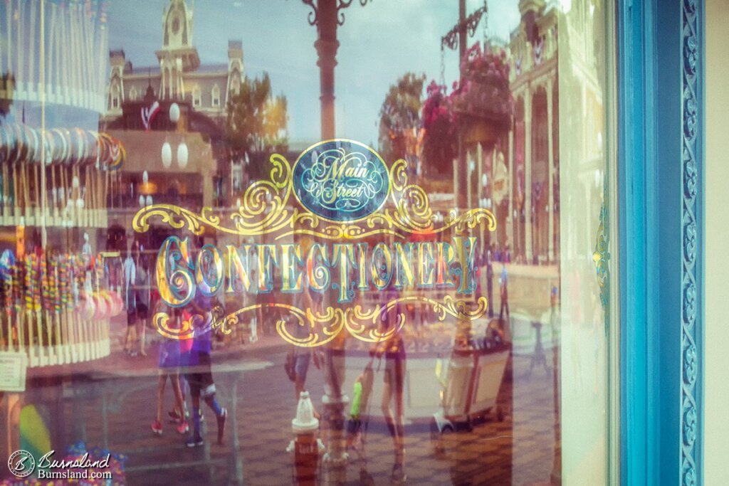 The buildings of Main Street USA are reflected in the window of the Main Street Confectionery in Walt Disney World’s Magic Kingdom. Read all about it at Burnsland!