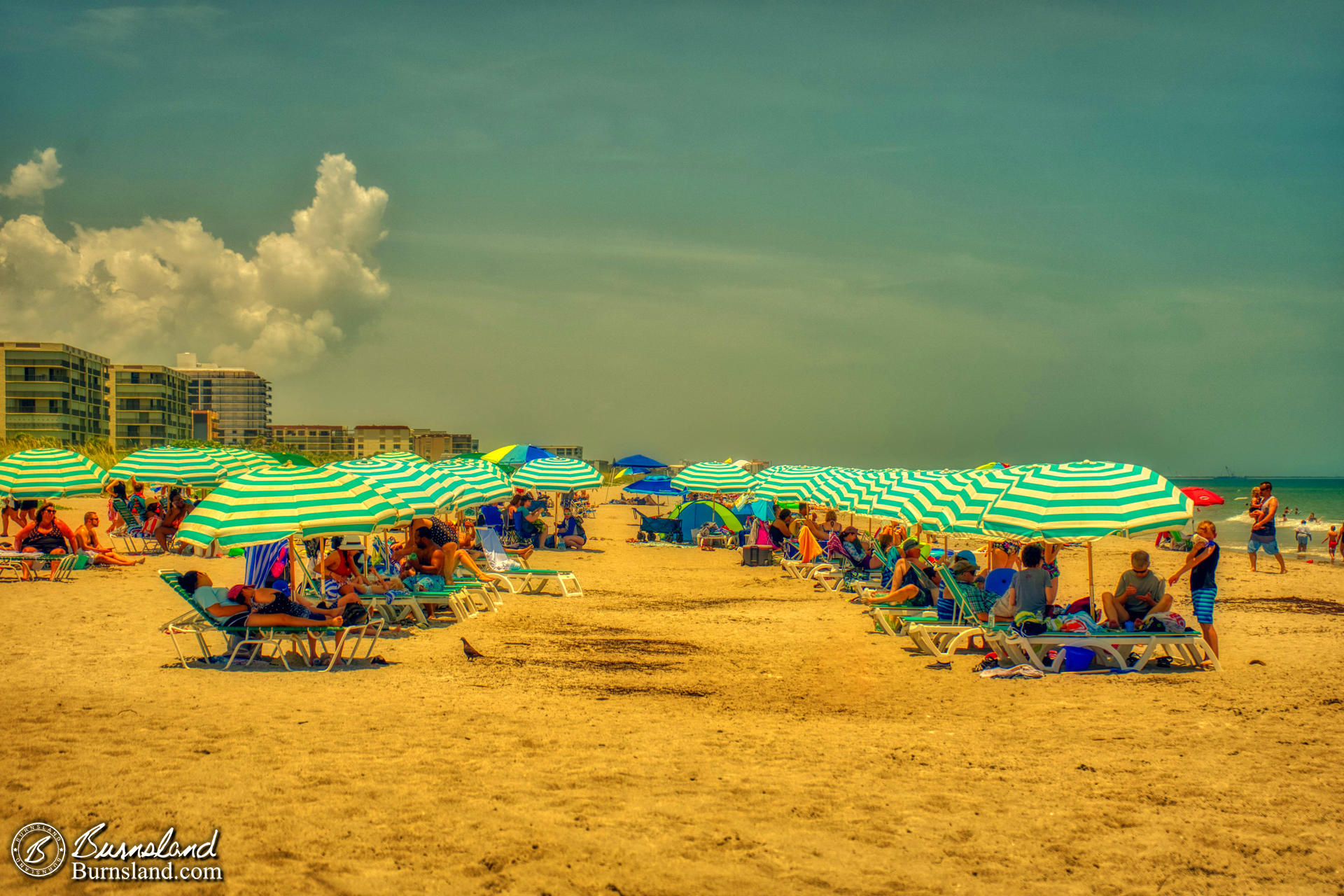 Rows of striped beach umbrellas fill the sand at Lori Wilson Park in Cocoa Beach, Florida