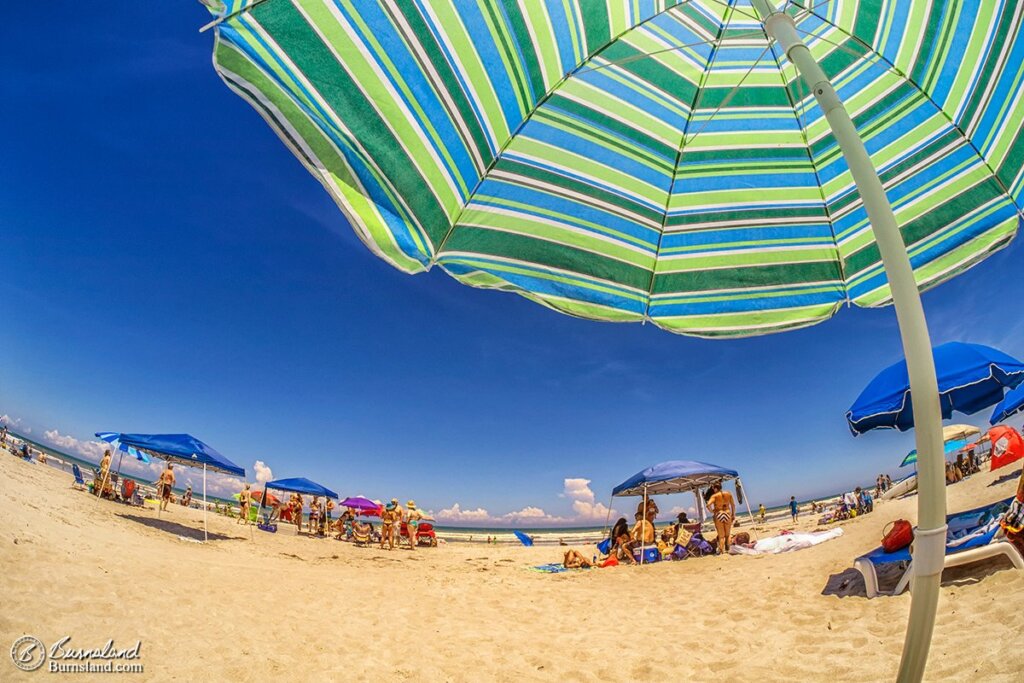 Our beach umbrella provides shade from the sun during a beautiful day at Cocoa Beach, Florida. Read all about it at Burnsland!