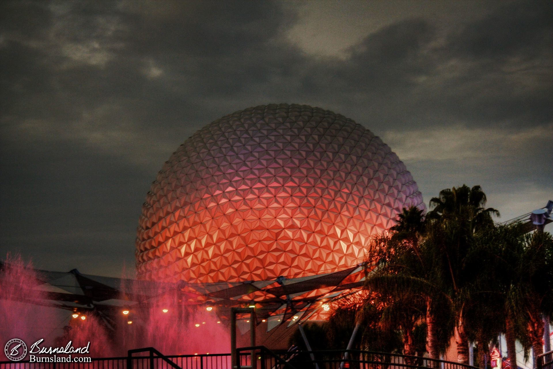 Spaceship Earth at Epcot in Walt Disney World rises in the night against a cloudy sky.