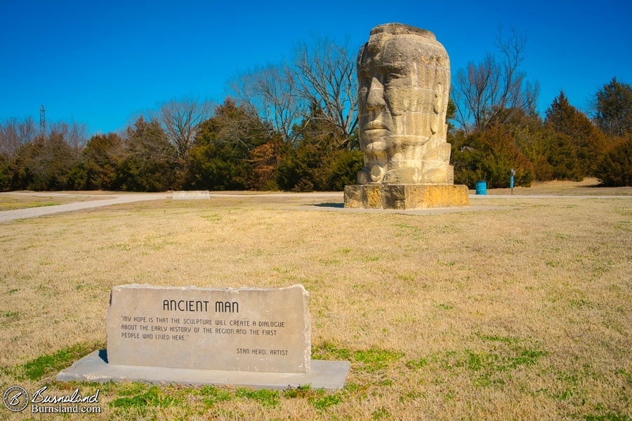 A large stone “Ancient Man” statue by artist Stan Herd in a park in Parsons, Kansas