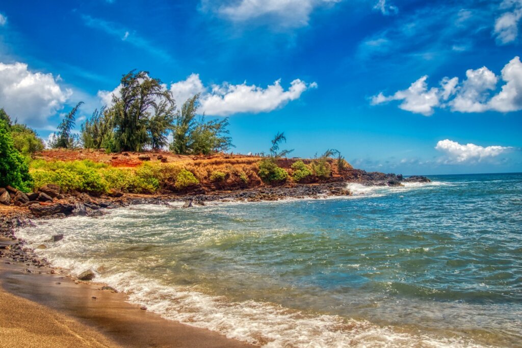 Waves, sand, clouds, and a beautiful blue sky at Glass Beach near ʻEleʻele on the island of Kauaʻi in Hawaiʻi, in a photo reduced in size using ImageMagick.