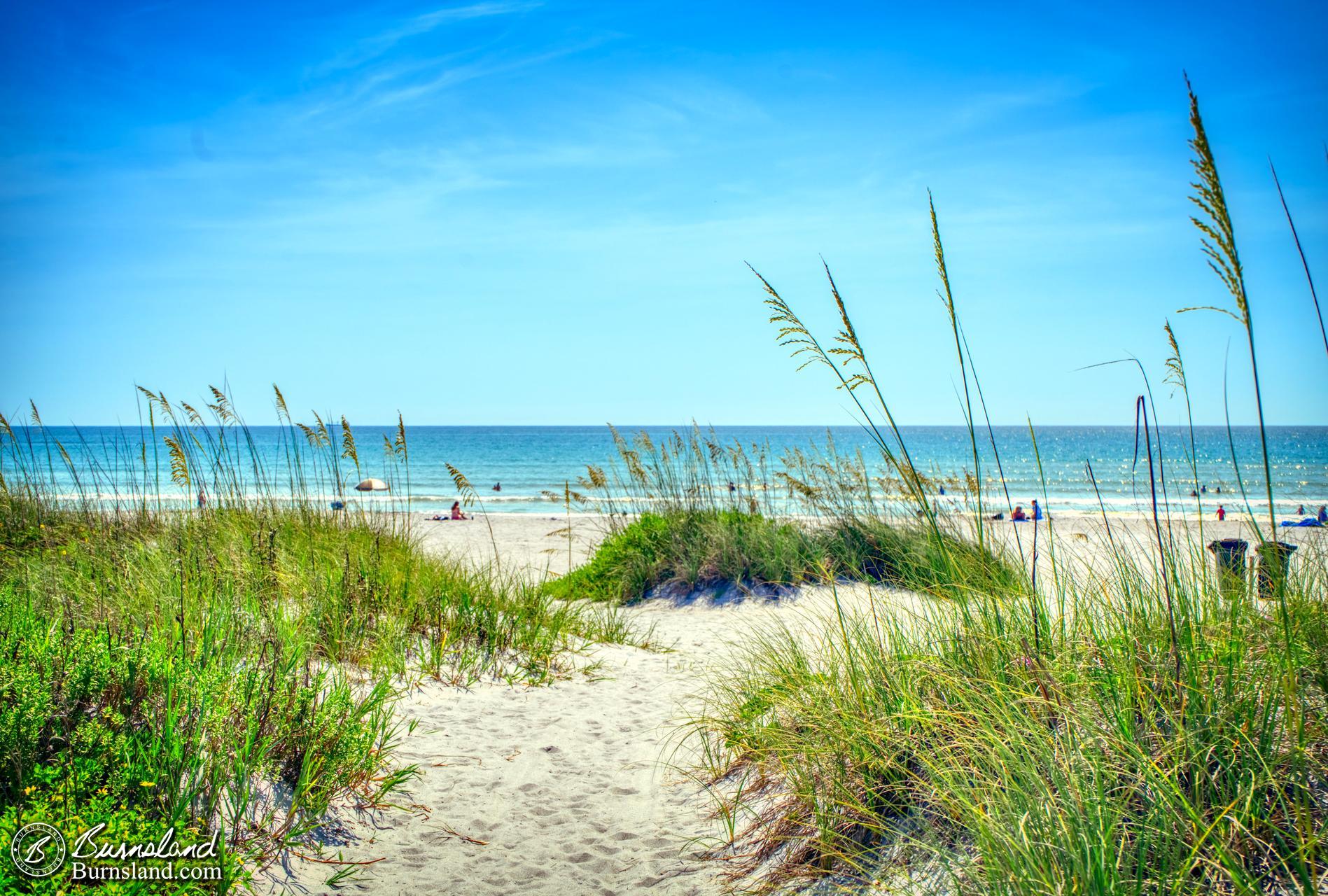 The sun shines down on the sand and the sea oats at Lori Wilson Park in Cocoa Beach, Florida