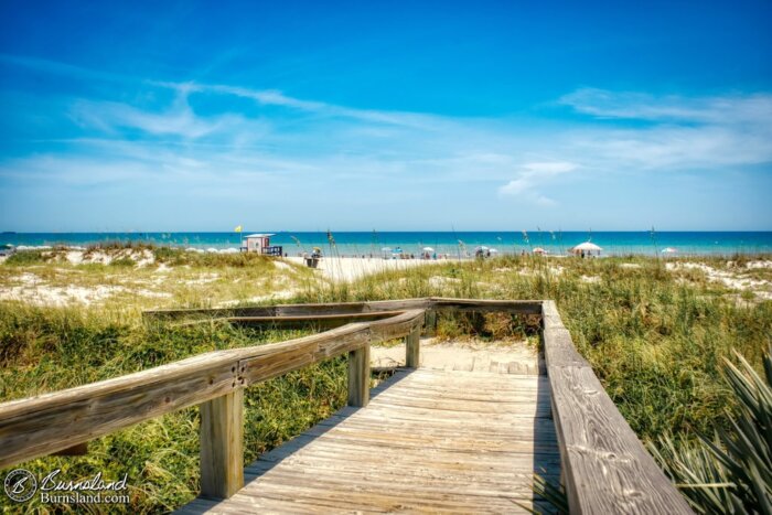 A wooden boardwalk walkway leads over the sand dunes and out to the beach at Lori Wilson Park in Cocoa Beach, Florida