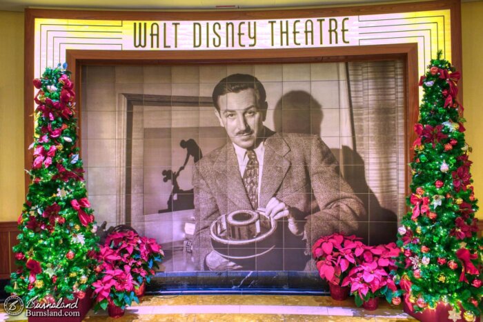 Christmas Trees and poinsettias surround the tile mural outside of the Walt Disney Theatre on the Disney Dream